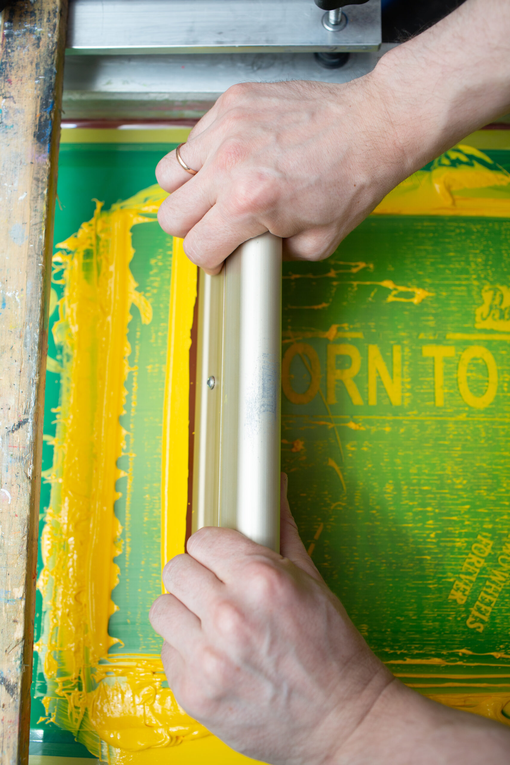 Serigraphy silk screen print process at clothes factory. Frame, squeegee and plastisol color paints.